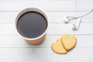 Black coffee in a paper cup and cookies in the shape of hearts on a white background. flat lay copy space, top view.