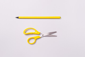 Scissors and pencil on a white background. Materials for preparation for decoration for the holiday.