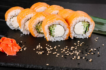 Tasty sushi rolls with salmon on black background