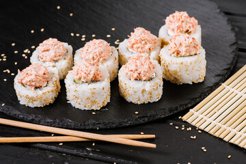 Delicious white sushi rolls with salmon sauce on black background
