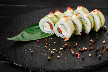 Delicious avocado sushi rolls on black background