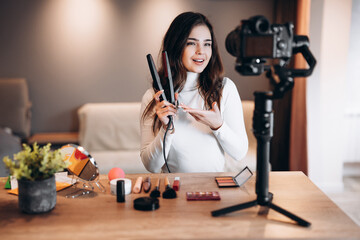 Beauty blogger nice female filming daily make-up routine tutorial on camera. Influencer young woman...