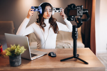 Pretty blogger woman in headphones is streaming live talking about video games. Influencer young woman is having fun live streaming