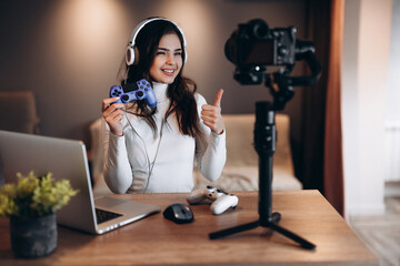 Pretty blogger woman in headphones is streaming live talking about video games. Influencer young...