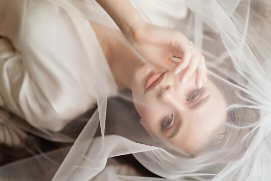 view top. a beautiful young woman in robe is lying under a veil.