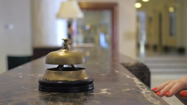 Hand of a young girl using a service bell in hotel reception