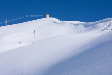Snowfall. Pristine deep white snow drifts. Sun reflects on the snow in the winter Alps.