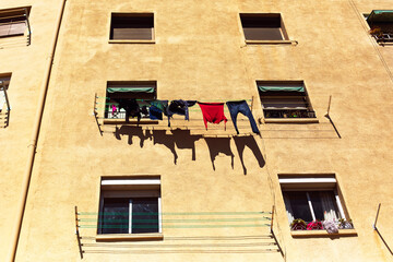 Drying laundry outside the window in yellow residential multi-apartment house in Barcelona, Spain