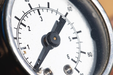Close-up of an old industrial pressure gauge display with worn protective glass. Macro