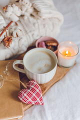 Ecodecor for the home. Home cozy decor. A mug of cappuccino, cookies, a candle on the bed. Winter morning.