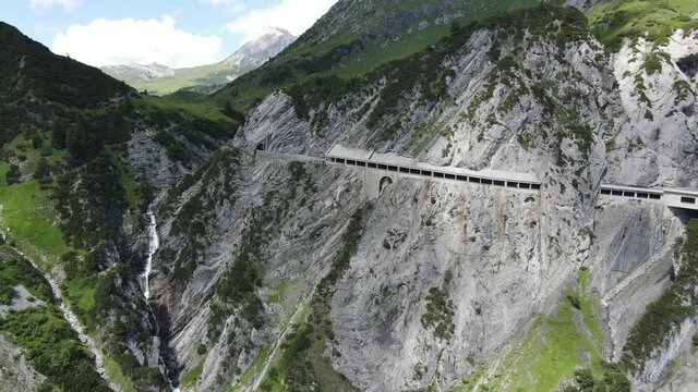 eine gallerie in form einer bergsstraße führt durch fels und wiesen und schlängelt sich durch die alpen des arlbergs