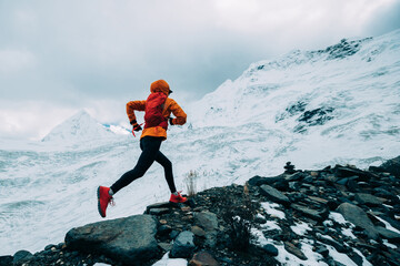 Woman trail runner cross country running up to winter snow mountain top