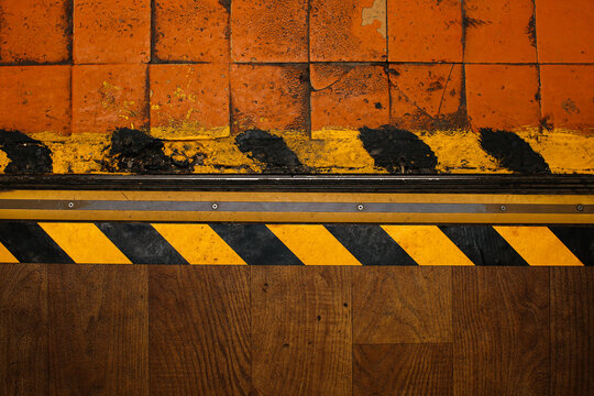 Floor danger zone warning tape yellow with black. Caution - danger. Old vintage wallpaper. Texture background room factory production. Wood and tile.