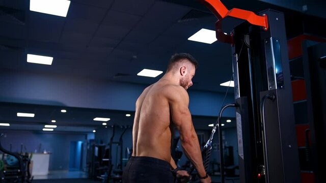 Fit muscular man is exercising with sport equipment. Muscular young man is lifting weights on gym background with blue light filter.