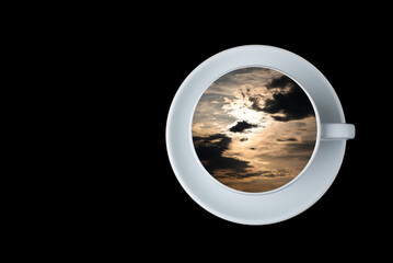 sunset in the sky reflected in a white coffee cup on a black background. copy space.