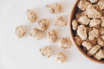 Raw dehydrated soy meat or dry soya chunks in wooden plate on white background. Top view. Copy, empty space for text
