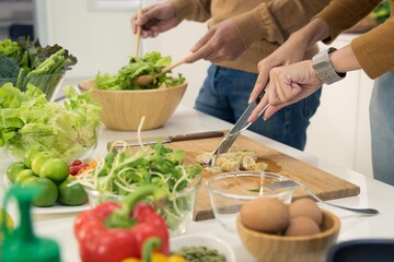 Asian woman and man couple family preparing vegetables on cutting board to make healthy food salad in modern kitchen room