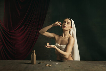 Healthcare. Modern remake of classical artwork with coronavirus theme - young medieval woman on dark background posing with medicine and pills. Concept of coronavirus, pandemic, creativity.