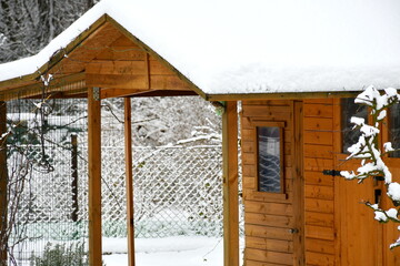 Close up on a wooden shack located in the middle of the forest or moor with snow covering it and with some decorative elements clearly visible seen in Poland in winter right after snowfall