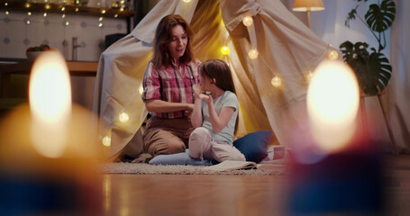 Mother and daughter in teepee tent combing hair and chatting