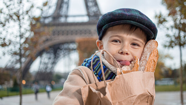 Adorable small boy eating a french bread over Eiffel tower	