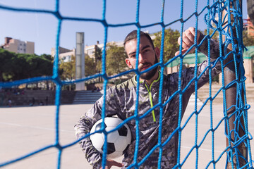 portrait of a footballer through the goal net