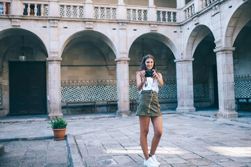 Fototapeta na wymiar Happy female tourist taking pictures in courtyard