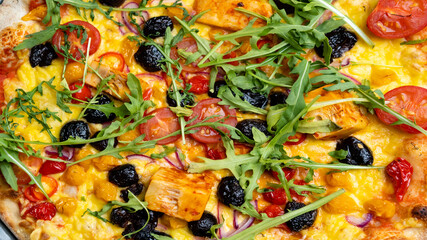 Black olive, tomato and rocket pizza close up 