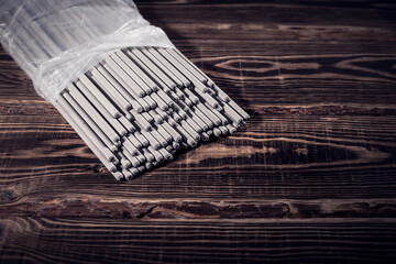 Open pack of welding electrodes on a wooden background. Studio photo in hard light.