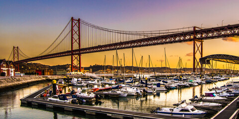 Barcas amarradas en el puerto bajo el Puente colgante 25 de abril sobre el tajo en Lisboa al...