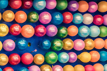 Globos de colores en una atracción de feria y un dardo rosa explotando un globo
