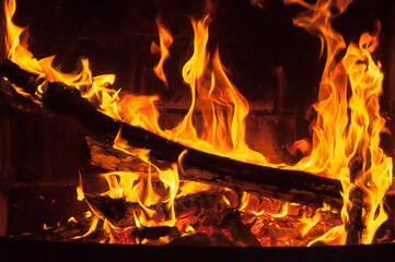 Detalle de fuego y llamas quemando una madera en una chimenea