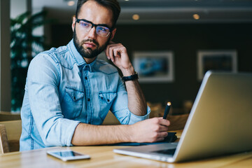 Serious man with laptop in modern workspace