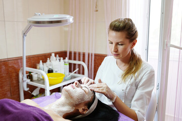 Obraz na płótnie Canvas Face Lifting. Young woman getting facial scrub in the cosmetology salon