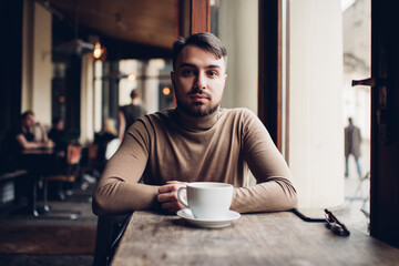 Thoughtful young man drinking hot coffee in cafe