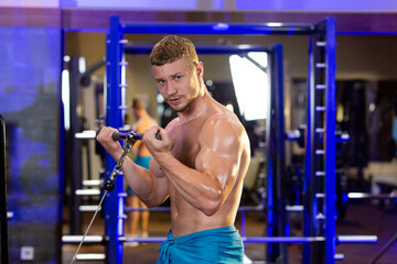 Blond male athlete performs fitness exercises in the gym