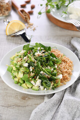 Fototapeta na wymiar Gluten-free green vegetarian salad made of microgreen sprouts peas, avocado, quinoa, spinach, seasoned crushed almonds with slices of feta cheese