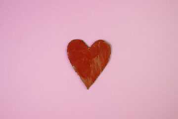 Cardboard heart on a pink background. An inaccurately painted heart. Red heart. Health concept