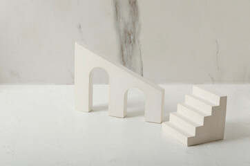 White geometric platforms for product presentation on the white desk against marble wall