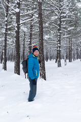 Fototapeta na wymiar Handsome bearded caucasian man standing in a snowy pine forest. Winter outdoor activities.