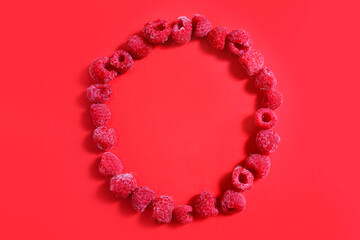 Obraz premium Berries of Frozen raspberries are laid out in a circle on a red background. frozen food concept. Top flat lay view. monochrome