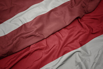 waving colorful flag of indonesia and national flag of latvia.