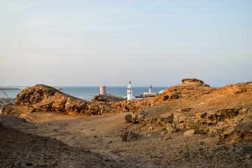 Fototapeta na wymiar View of a tower, the minaret of a mosque and Al Ayjah Lighthouse from the mountains that surround it. Sur, Oman.
