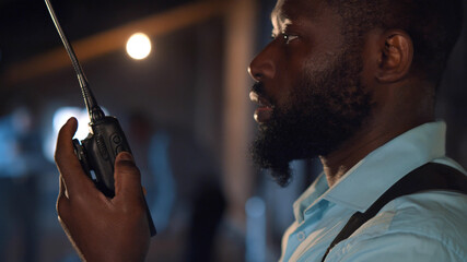 Close up of african policeman talking on radio set at crime scene with corpse