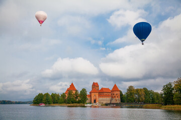Fototapeta na wymiar Trakai Island Castle and two air balloons flying above