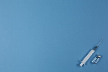 Syringe and vaccine on blue background