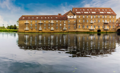 Fototapeta na wymiar The mill at Riverside, Godmanchester reflected in the calm waters of the River Great Ouse in springtime