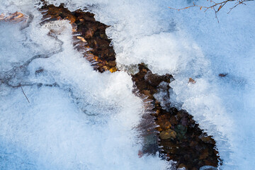 Cracked ice on a smal brook with some gravel underneath