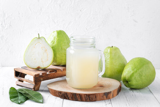 Delicious guava fruit with fresh juice set on white wooden table background.