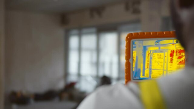 Close up of african builder analyzing heat on wall with thermal imaging camera app on tablet